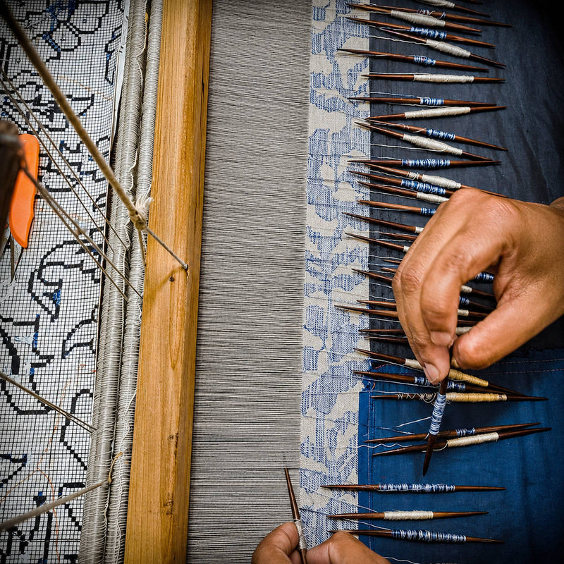 Person weaving Kaani Shawl with a loom at Ezma Gurgaon, focusing on the intricate process of textile creation in cashmere